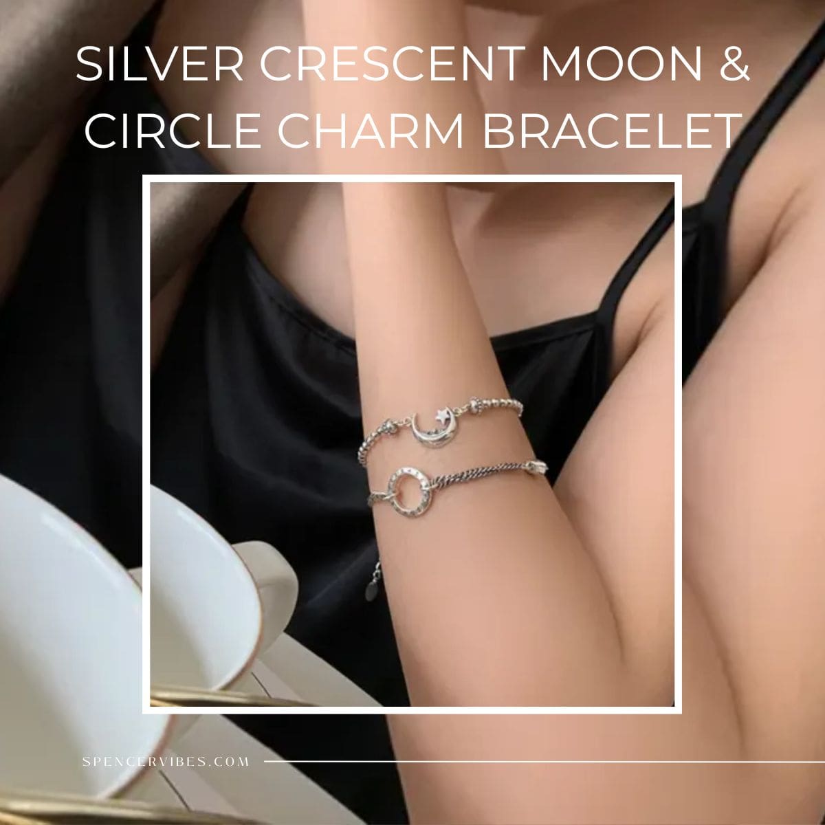A woman in a black camisole showcases the Silver Crescent Moon & Circle Charm Bracelet set—two elegant silver bracelets, one with a crescent moon charm and the other with a circle. The close-up photo features stylish, sophisticated lighting.